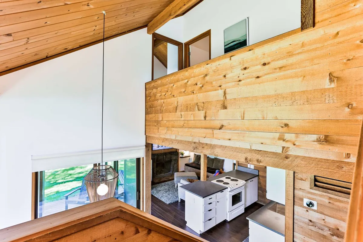 A cozy open kitchen with striking wooden beams and large windows, allowing plenty of natural light. The space feels welcoming and communal, perfect for preparing meals with family or friends while enjoying views of the outdoors.